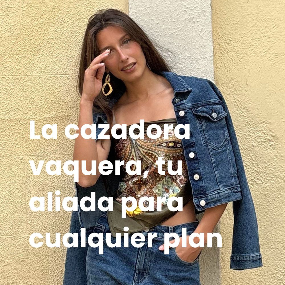 Chica morena con cazadora vaquera azul oscuro, top de estampado verde brillante y pantalones vaqueros azules.